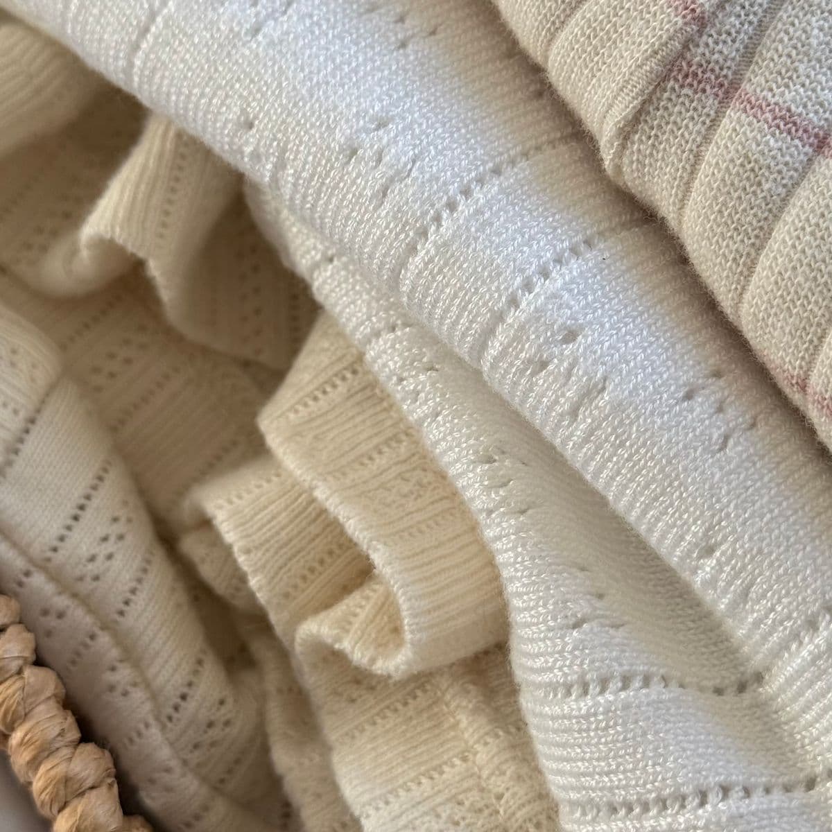 Folded cream pointelle-knit baby garments