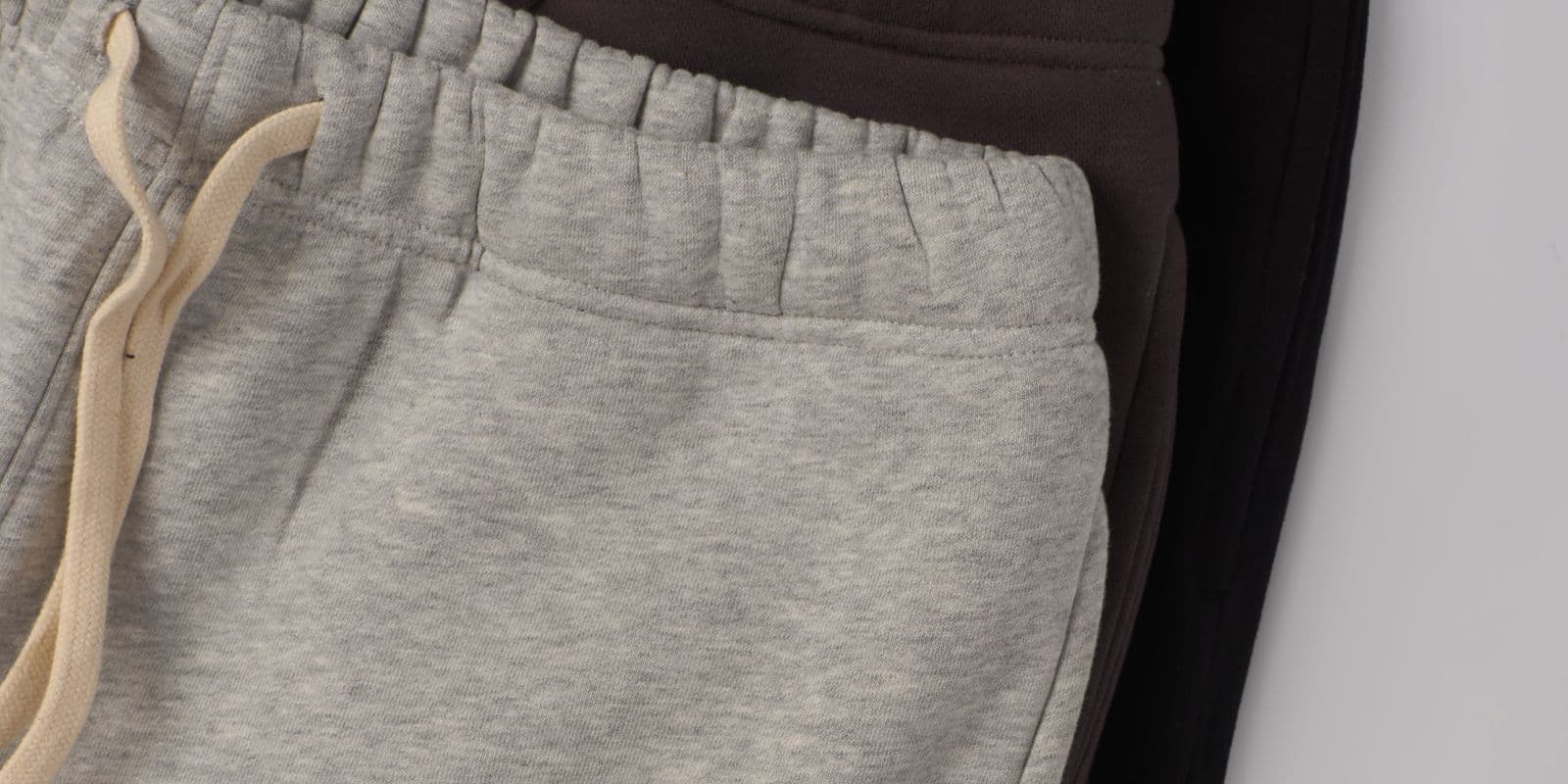 Folded grey, charcoal and black joggers in a row